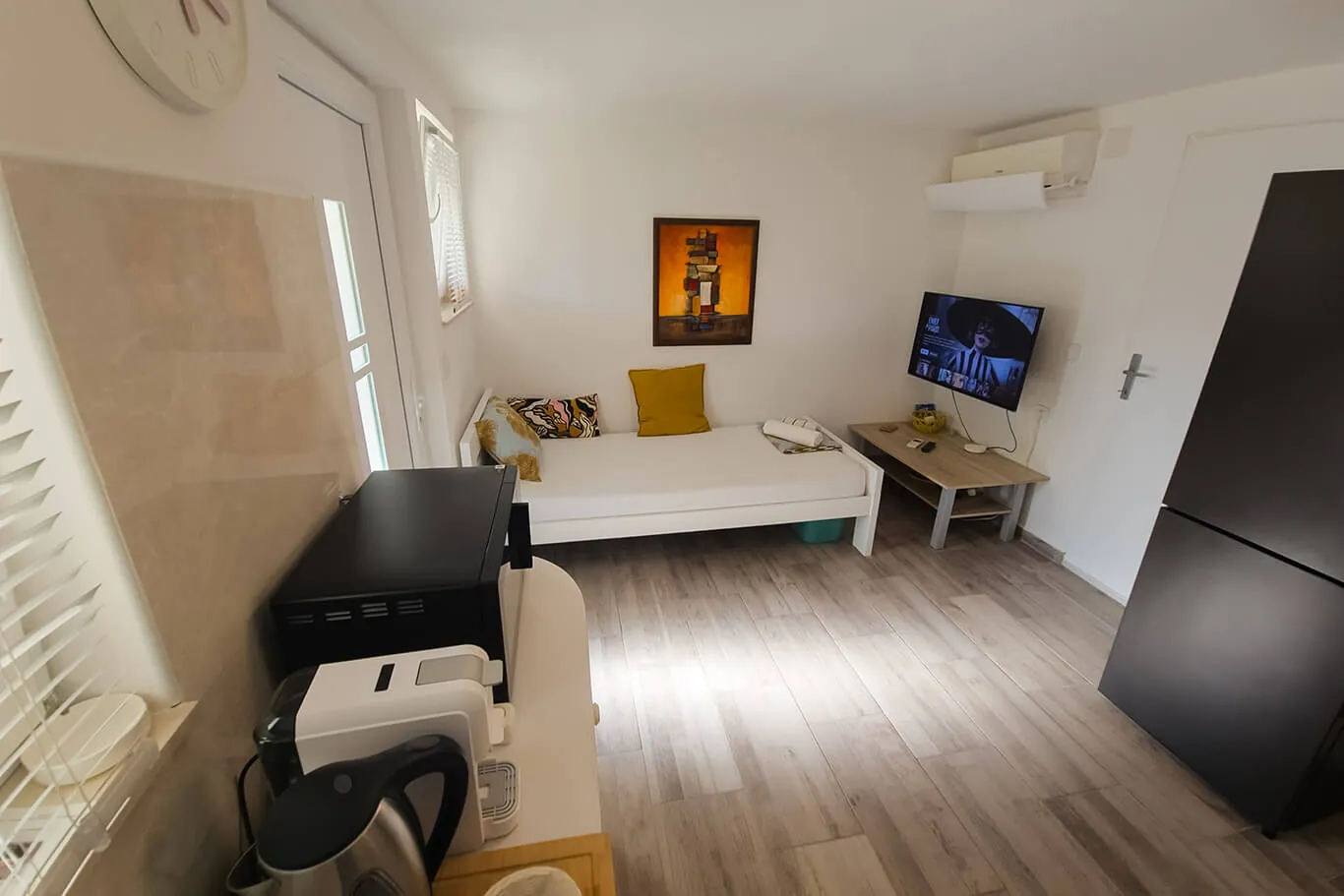 Third bedroom with a convertible bed, TV, AC and an orange abstract art print