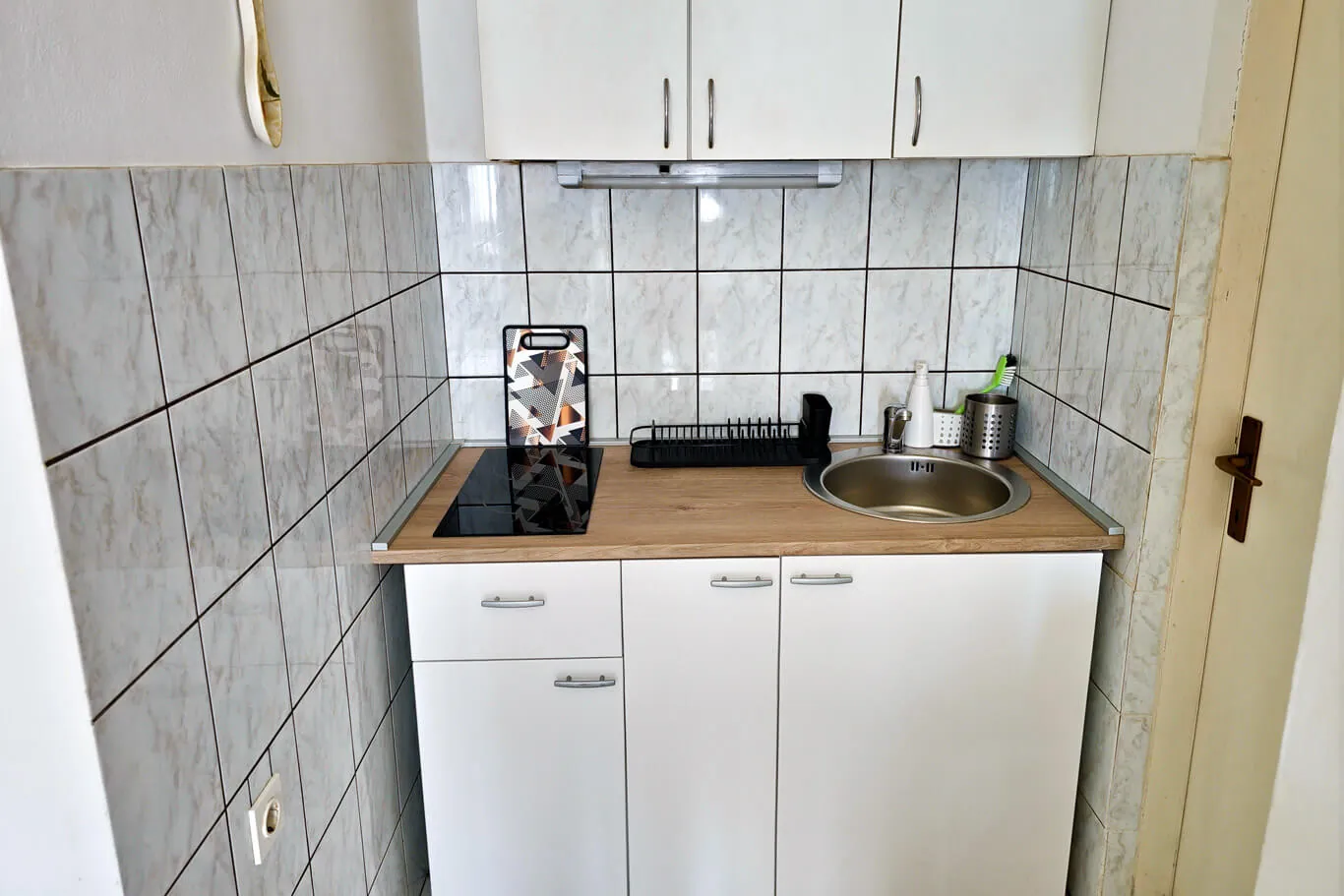 Teja: compact kitchen with marbled tile and wood counter
