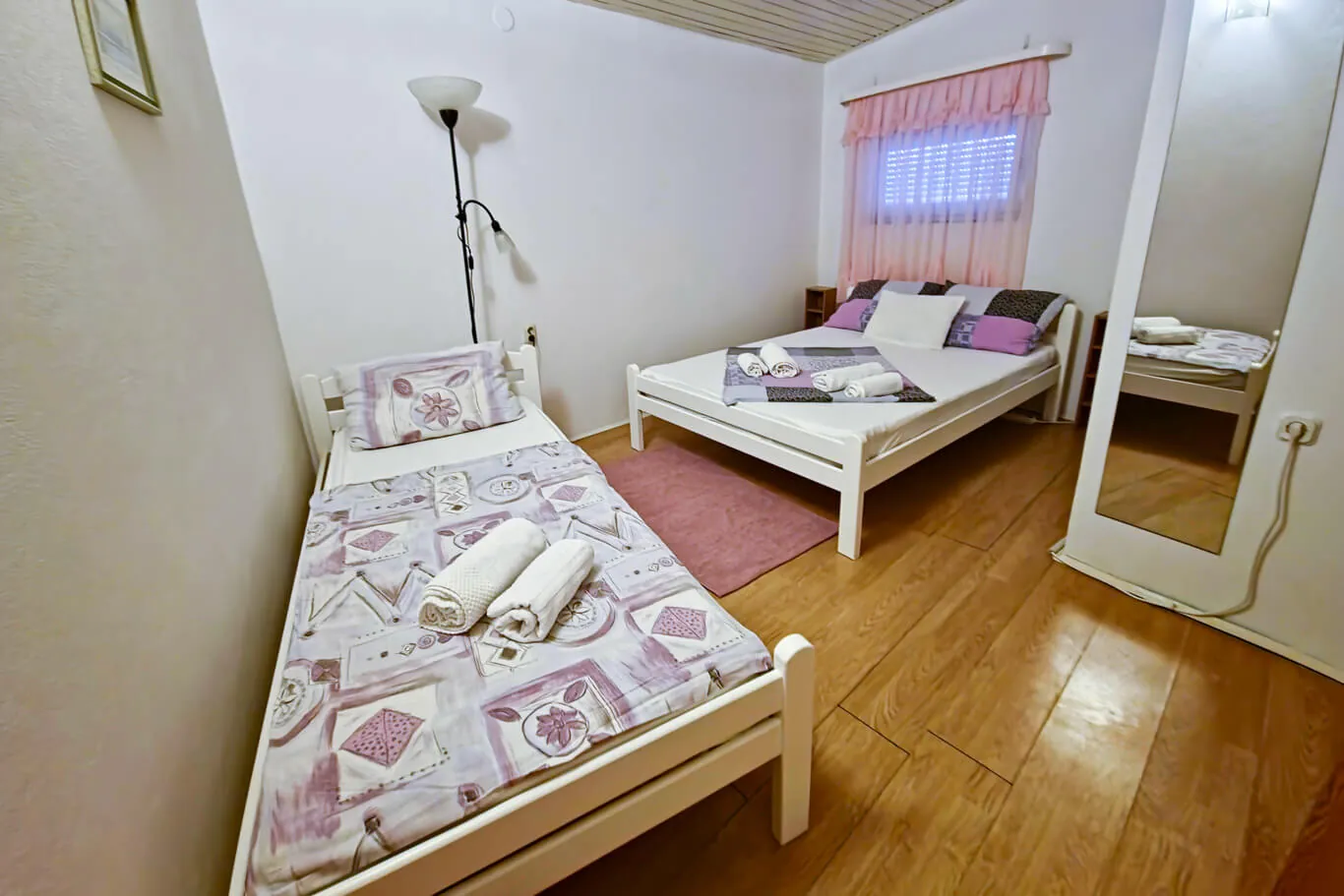 Second bedroom with a single bed, double bed, pastel pink curtain and mirror