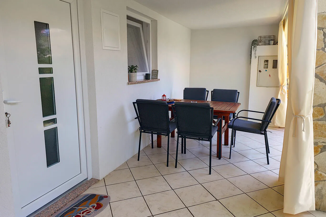 Covered entry area with dining table and dark chairs
